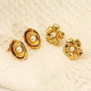 Floral gold-tone earrings with pearls and irregular metallic texture on woven fabric