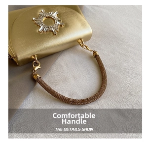 Detail of luxury gold evening clutch bag with crystal sunburst pattern and jeweled handle