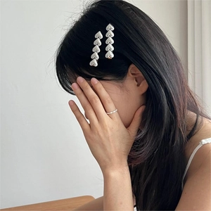Close-up of five silver heart-shaped hair clips worn on elegant long dark hair