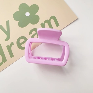 Detail of a matte pink square hair claw clip placed against a white background