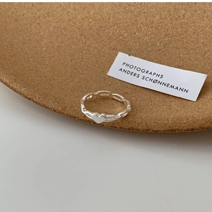 Detail of silver chain ring with heart design on textured brown background