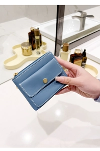 Detailed view of a blue PU leather key pouch with gold snap and zipper being held
