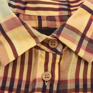 Détail d'une chemise en lin à carreaux avec boutons marrons et texture de tissu vintage