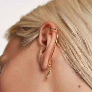 Close-up of golden ear cuff with colorful gemstone tassels and sparkling diamond details