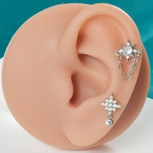 Détail de boucles d'oreilles étoiles argentées avec zircons sur un modèle d'oreille