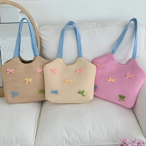 Detail view of woven beach bags with colorful bow accents in khaki, white and pink