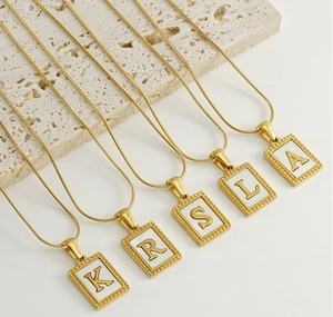 Detail of 18K gold plated snake chain necklaces with square white letter pendants