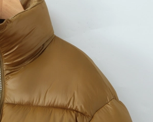Detail of quilted mustard yellow stand-up collar puffer jacket with dual zipper design
