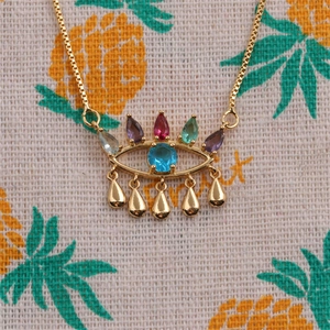 Macro shot of gold Evil Eye necklace with colorful gems and five teardrop pendants
