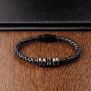 Braided black leather bracelet with silver metal beads on a rustic wood texture