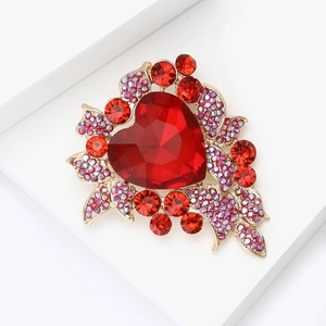 Close-up of heart brooch with red gemstones and purple crystals on gold metal base