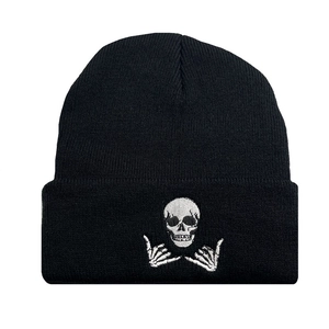 Black ribbed knit beanie with white skull and bone hand embroidery on white background