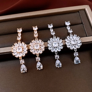 Detail view of crystal floral tassel earrings in gold and silver plating with zircons