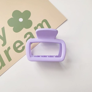 Close-up of a matte lavender rectangular hair claw clip on a decorative card background