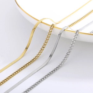 Detail of gold and silver flat snake chains and Cuban links on a white ceramic tray