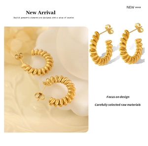 Macro detail of twisted gold titanium steel C-shape hoop earrings with spiral texture