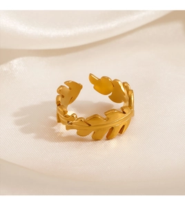 Detail of adjustable golden leaf ring on white satin fabric showing matte metal texture