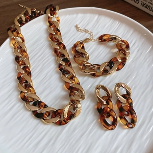 Macro detail of amber resin and gold linked jewelry set on white ceramic tray