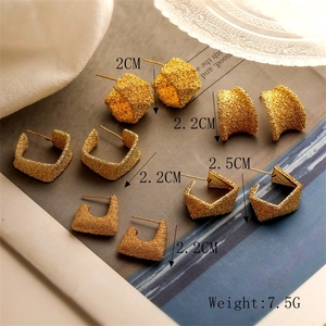 Close-up of matte gold geometric earrings showing sizes from 2cm to 2.5cm