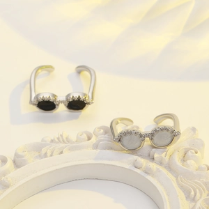 Macro shot of miniature sunglasses rings with black and white stones on relief base