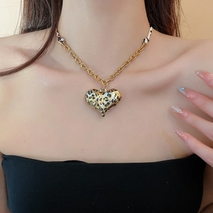 Detail of chunky gold chain necklace with a leopard print heart pendant on model