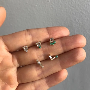 Detailed view of 925 silver gold studs with emerald gems held in a palm for scale