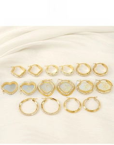 Flat lay of gold titanium steel earrings in heart and geometric shapes on white silk
