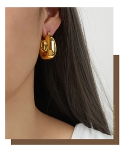 Macro detail of thick gold-plated U-shaped geometric earrings on model with high polish finish