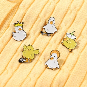 Set of five cartoon enamel pins featuring duck and chicken figures on knit fabric