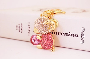 Close-up of golden sheep keychain with sparkling pink and clear crystals on a book