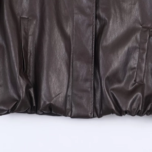 Detailed view of dark brown leather jacket hem, front placket, and side pockets texture