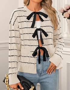 Detail view of cream cardigan with black stripes and elegant ribbon tie closures