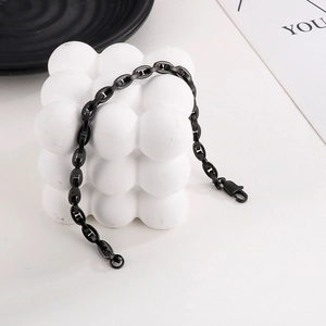 Close-up of black coffee bean link chain bracelet with lobster clasp on white prop