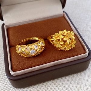 Macro shot of two gold flower rings with crystals inside a brown velvet jewelry box
