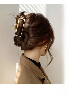 Close-up of a matte gold rectangular metal hair claw clip holding a stylish updo hairstyle