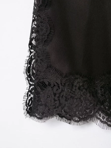 Gros plan sur un tissu en satin noir avec bordure en dentelle cil et finitions fines