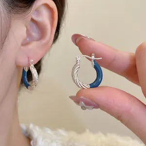 Silver hoop earrings with blue enamel contrast and textured twisted metal finish