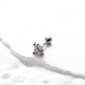 Macro view of silver four-petal flower cartilage stud with pearl-like inlay and ball back