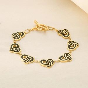 Detail view of gold stainless steel bracelet with black enamel knots and OT toggle clasp