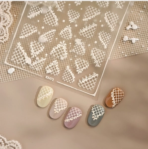 Macro detail of white lace and grid nail art stickers on various colored base tips
