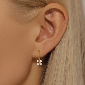 Close-up of gold flower earrings with opal inlay and clear crystals worn on model