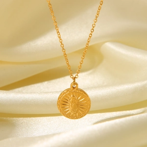 Macro detail of 18K gold plated necklace with angel relief pendant on silk fabric