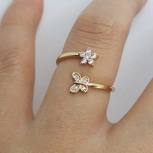 Macro view of gold butterfly and flower ring with sparkling white cubic zirconia on finger