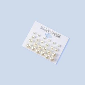 Detailed view of 12 pairs of white pearl earrings in various sizes on a display card