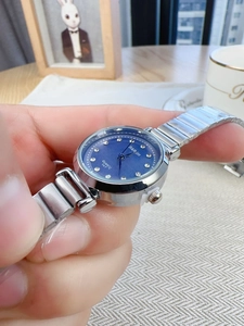 Close-up of women's silver quartz watch featuring a blue dial with crystal markers