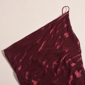 Détail du tissu en maille bordeaux avec texture ondulée métallique et fine bretelle