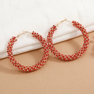 Close-up of gold circle earrings with sparkling red rhinestones on soft fabric