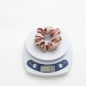 Detailed shot showing a pink satin scrunchie on a scale weighing exactly 9.2g