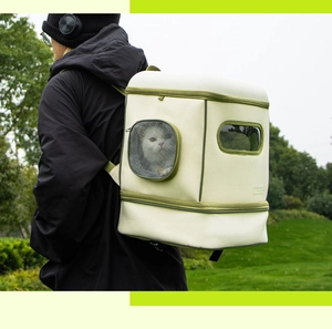 Detail of model wearing the beige and green pet backpack with mesh window outdoors