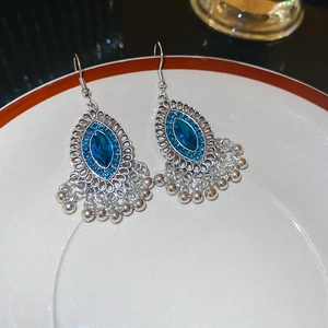 Dettaglio di orecchini vintage in argento con gemme blu e piccoli campanelli